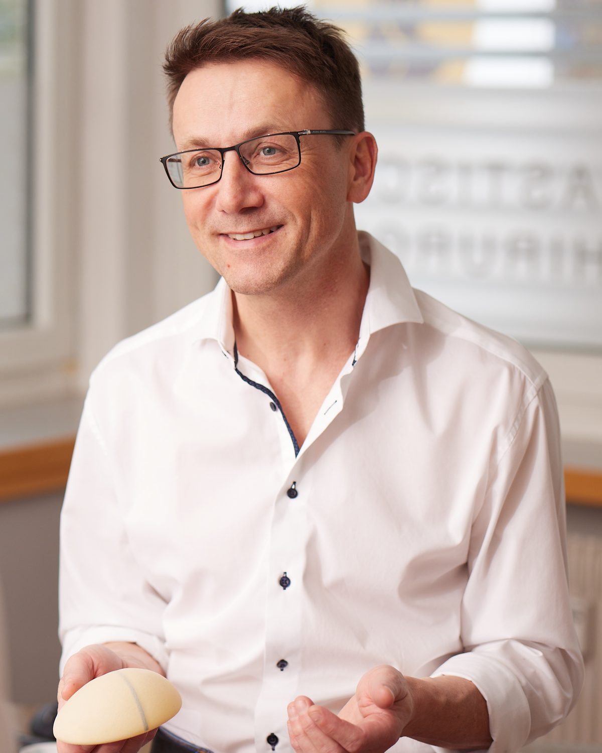 Dr. med. Holger Osthus erklärt im Beratungsgespräch ein Brustimplantat